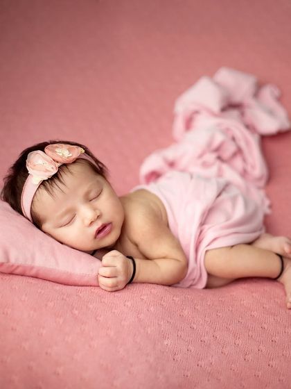 Pretty in pink. This simple and elegant setup uses a soft pink blanket and pillow to create a delicate and feminine portrait of a sleeping newborn girl.