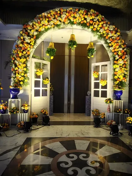 A beautiful and welcoming entrance for a Haldi ceremony. The combination of a dense marigold floral arch, hanging bells, and blue pottery creates a look that is both traditional and trendy.