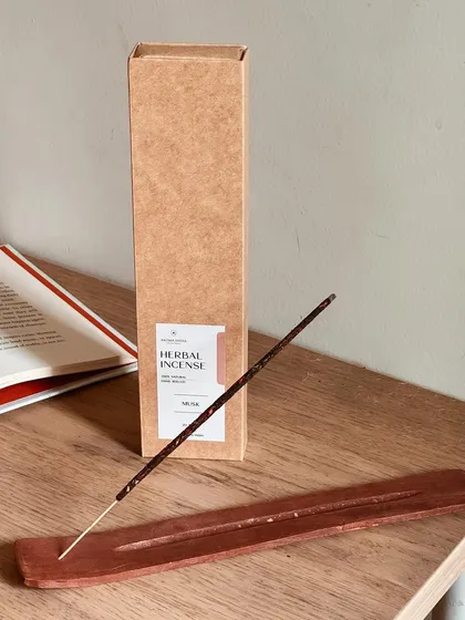 Our herbal incense stick rests in a simple wooden holder, ready to be lit. Using incense can help you connect with your creativity and find inner peace during your daily rituals.