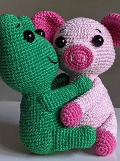 A pair of inseparable friends, a green frog and a pink pig, sharing a hug. I make these crochet animal buddies as a set, perfect for gifting.