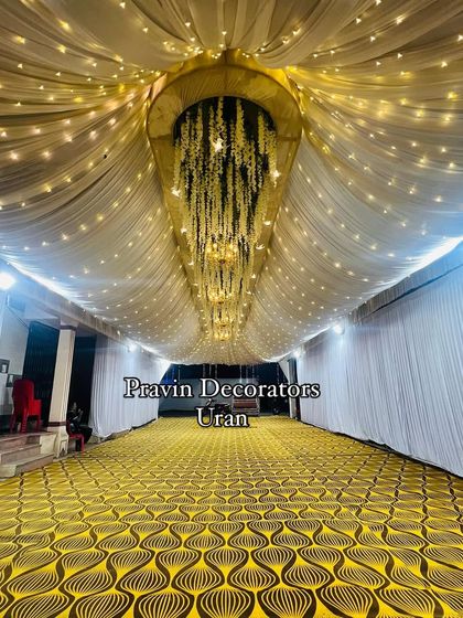 A stunning ceiling treatment we created for a long passageway. We used draped fabric with twinkling fairy lights and a central structure with hanging yellow flowers to create a magical atmosphere.