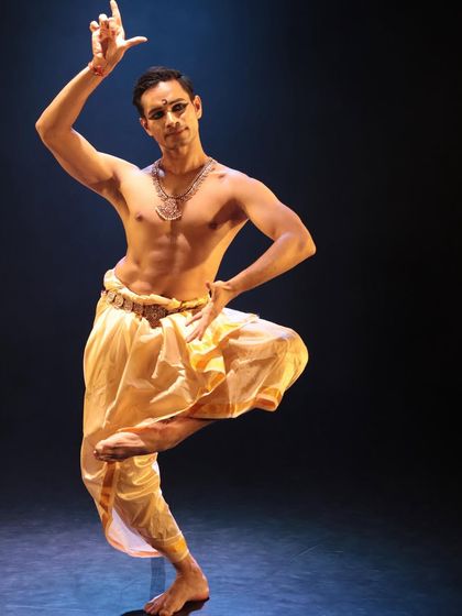 A studio shot capturing a classic Bharatanatyam posture. The geometry and lines of the body are fundamental to this dance form.