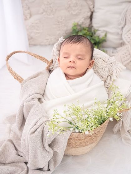 Nestled in a basket with soft blankets and a touch of greenery, this portrait has a fresh, natural, and timeless quality.