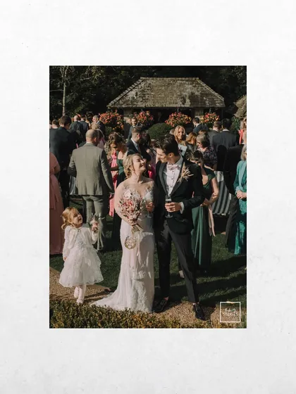 A candid moment from a wedding in Bibury, UK, with the couple mingling with their guests. The image captures the joyful, relaxed atmosphere of a garden party celebration.