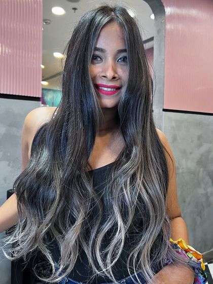 A dramatic signature balayage with a high contrast between the dark roots and the ashy, almost silver ends. A bold and beautiful statement.
