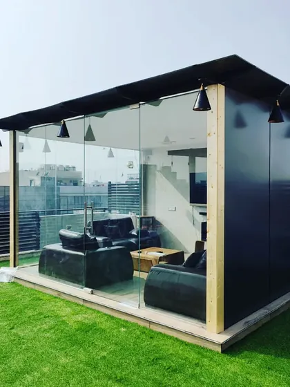 A sleek and modern glass room on a rooftop, providing a comfortable, air-conditioned lounge with a 360-degree view.