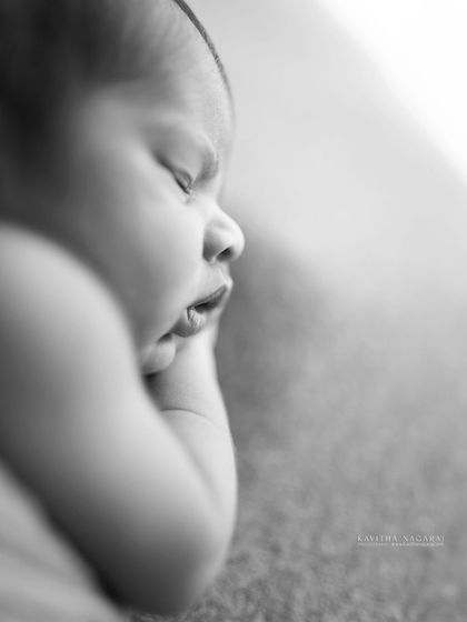A black and white macro shot of a newborn's face. The soft focus and close crop create an artistic and emotional portrait that you will treasure.