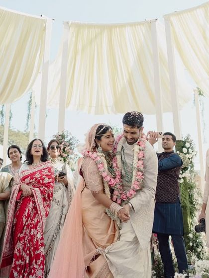 The couple during their jaimala ceremony, surrounded by guests under the beautiful draped canopy.