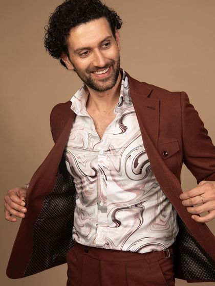 A rust-colored suit with a printed shirt, offering a refined safari-style look. This is for the man who wants an outfit that is ready for adventure.