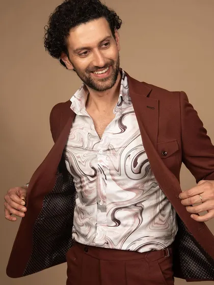 A rust-colored suit with a printed shirt, offering a refined safari-style look. This is for the man who wants an outfit that is ready for adventure.