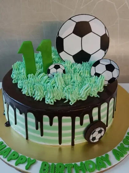 A fun football-themed drip cake for an 11th birthday. The green "grass" piping and soccer ball cutouts make it a great choice for a sports fan.