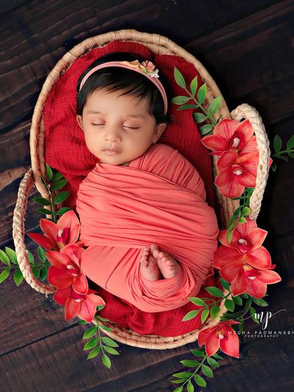 A top-down view of the baby sleeping soundly in the basket, surrounded by red flowers.