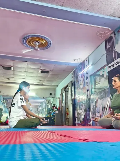 A coach and student meditate together, demonstrating that mental discipline is a journey shared by everyone in the academy, regardless of age or rank.