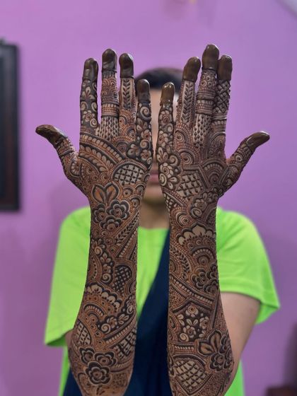 A fun pose showing off the full length of this engagement mehendi, from the fingertips to the elbow.