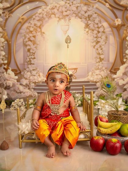 A moment of wonder in a divine setting. This wide shot shows the full scale of the Karthikeya-themed setup, with the baby sitting on a miniature golden throne.
