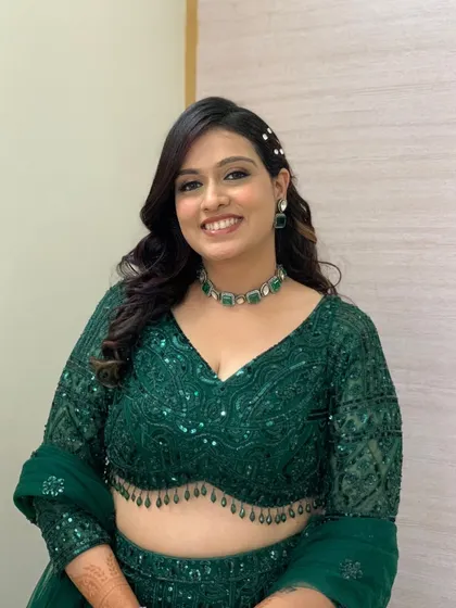 A stunning look in an emerald green lehenga, with soft glam makeup and beautiful curls.