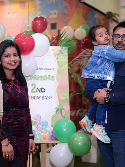 A family posing by the personalized welcome sign for their son's 2nd birthday bash.