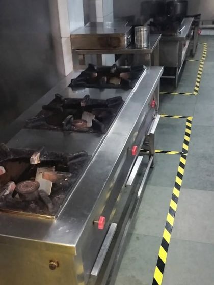 A close-up of our commercial-grade gas stove ranges. The kitchen is equipped with multiple burners to handle cooking for large-volume orders simultaneously.