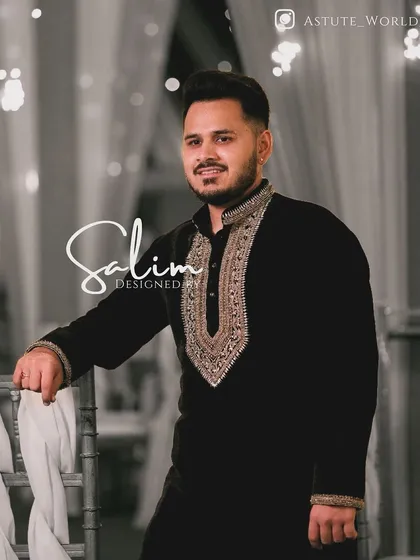 A client in a black velvet kurta with a heavily embroidered gold neckline and cuffs. This is a classic, regal look suitable for a wedding reception or formal dinner.