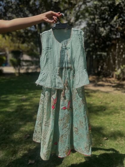 This mint green lehenga set with a peplum top is a fresh and modern take on festive wear. The printed skirt with bird motifs adds a playful touch to the elegant design.