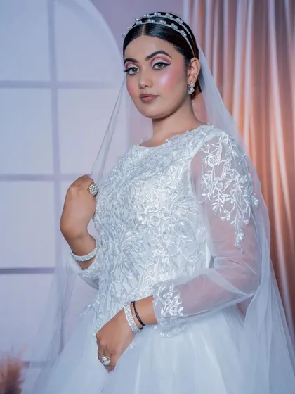 A three-quarter profile of the Christian bride, showing how the makeup and hairstyle look from the side, complementing the embroidered gown.