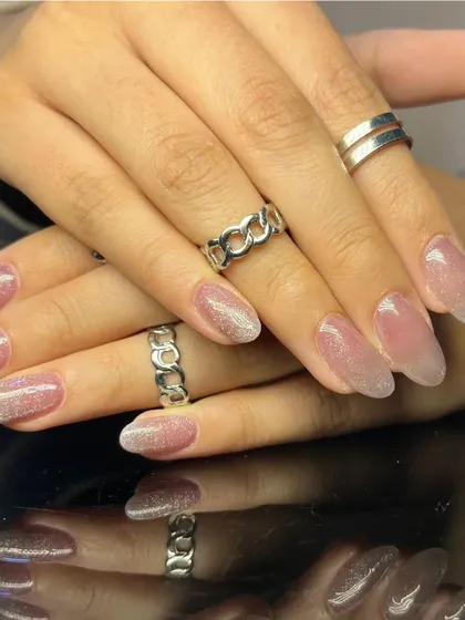 A full set of the elegant pink cat-eye nails, styled with delicate silver rings.