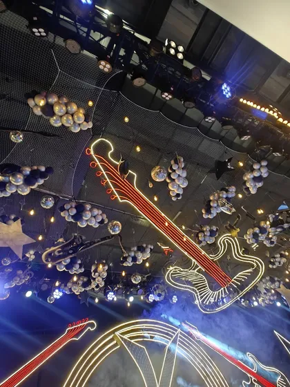 A different angle of the rock-and-roll ceiling decor, showing the interplay of lights, neon, and balloons. This image captures the dynamic and high-energy ambiance we can create for themed events.
