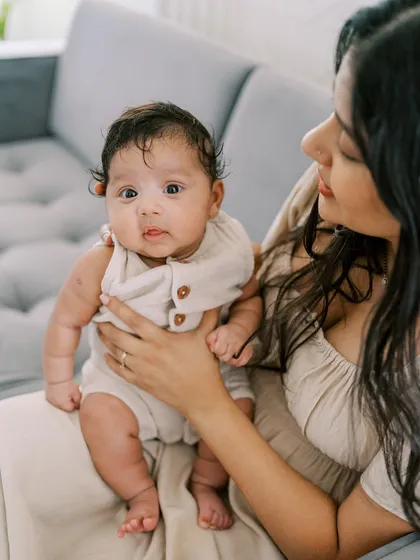 A mother holding her curious newborn. The baby's direct gaze and the mother's loving hold create a beautiful, connected portrait.