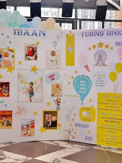 A personalized milestone board for Ibaan's first birthday. This large storybook-style display shares photos and fun facts from his first year, surrounded by a pastel balloon arch.