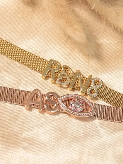 Customize your favorite piece. This image shows two personalized mesh bracelets with initials and an evil eye charm. You select the color, letters, and charms, and I'll deliver your personal jewellery to your doorstep.