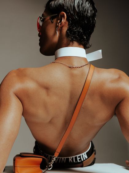 A shot from the back, focusing on the interplay between the model's physique, the branded choker, and a cross-body bag. This demonstrates how I consider every angle of a look.