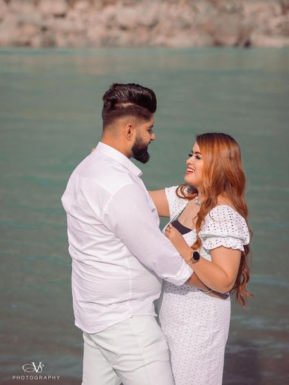 A beautiful, bright portrait of the couple sharing a laugh by the turquoise water, capturing a perfect pre-wedding memory.