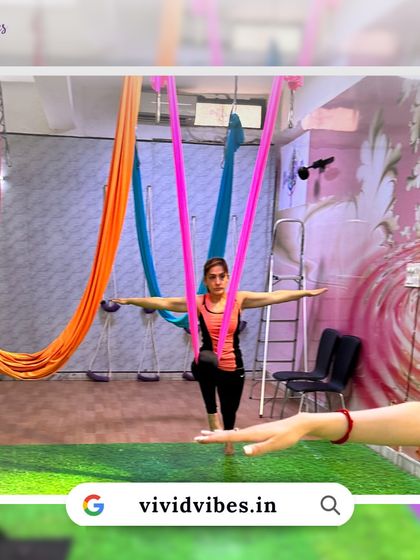 Fly high, live vibrant. This student is practicing a standing pose with the hammock, demonstrating balance and poise.