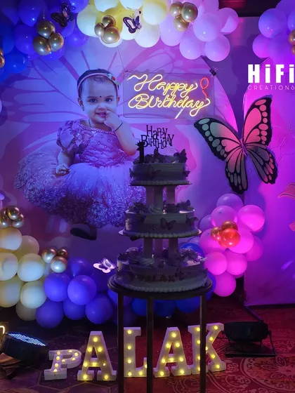 A sweet moment captured at the butterfly-themed party, with the birthday cake in front of the decor.