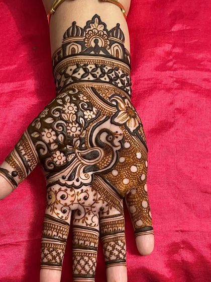 A graceful peacock and floral design on the back of the hand. The dotted patterns add a unique touch to this party-style mehandi.
