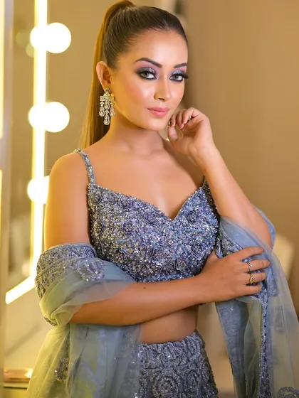 A three-quarter shot of the dusty blue lehenga, showing how the light catches the detailed embellishments. It's a subtle yet glamorous choice for an evening event.