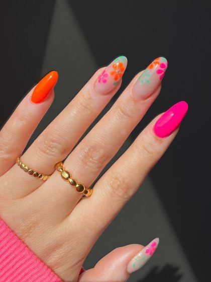 Bright and vibrant floral nail art. This design combines neon orange and pink with delicate floral patterns for a look that is pure summer fun.