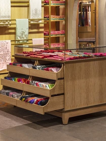 This custom display unit at Ahujasons features pull-out drawers with curved fronts, echoing the store's larger architectural gestures. Every detail is designed to enhance the user journey and reflect the brand's commitment to craftsmanship.