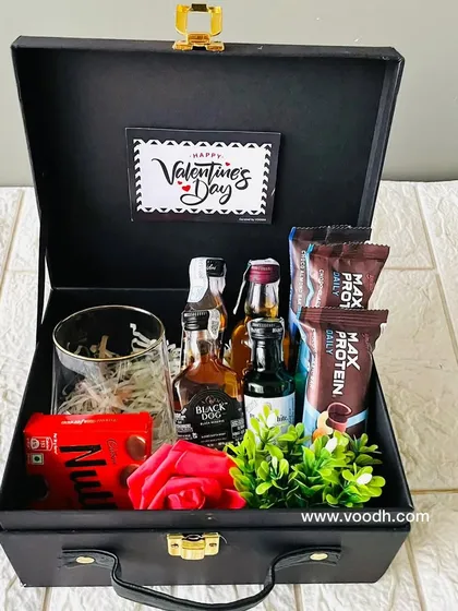 Another option for a men's Valentine's hamper in a black suitcase. This one includes protein bars, a whiskey glass, and miniature alcohol bottles.