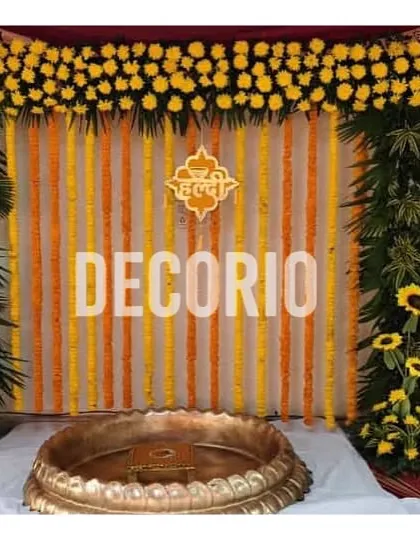 This is a classic Haldi ceremony backdrop that feels both traditional and fresh. I used strings of yellow and orange marigolds for the background, framed by a lush arch of greenery and sunflowers, to create a vibrant and auspicious setting for the pre-wedding ritual.