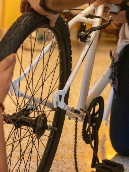 A close-up of a child's hands on the rear wheel and derailleur of a bicycle. It's in these focused moments of disassembly that the deepest learning happens.