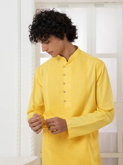 A detailed shot of the yellow pintuck kurta, showcasing the craftsmanship that goes into creating texture and interest in a minimalist design.