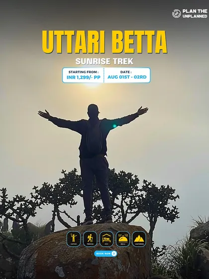 A trekker embraces the sunrise with open arms on the Uttari Betta sunrise trek.