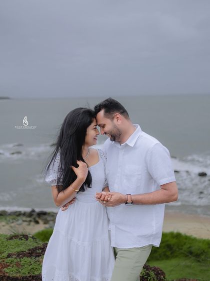 An intimate pose that conveys love and closeness, with the beautiful coastal view as a backdrop.