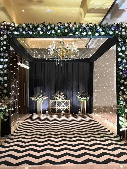 For a chic and modern cocktail night, we designed this stunning entrance. A bold black and white chevron walkway leads into the venue under a canopy of flowers and sparkling lights, setting a glamorous tone for the evening.