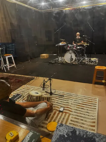 A wider view of the studio setup for our cross-cultural jam. My tabla setup is in the foreground, with the drum kit separated by a screen, showing a typical professional recording environment.