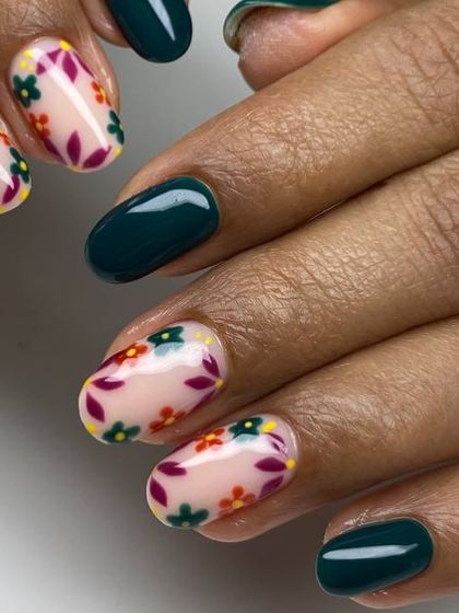 A beautiful and delicate floral nail art design. This set features a dark teal base with accent nails showcasing a hand-painted floral pattern on a sheer nude background.