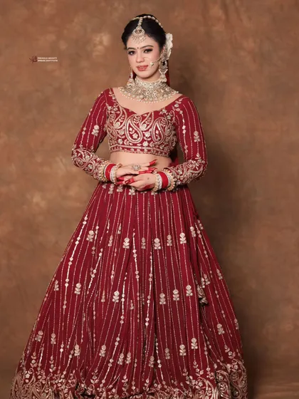 A full-length view of a bride in a magnificent red lehenga. The makeup is designed to be impactful even from a distance, ensuring you look stunning in all your wedding photos.