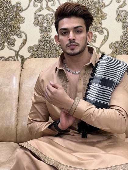 A relaxed moment in a custom-made beige Pathani suit. The fine embroidery and comfortable fit make it an ideal choice for festive gatherings at home.