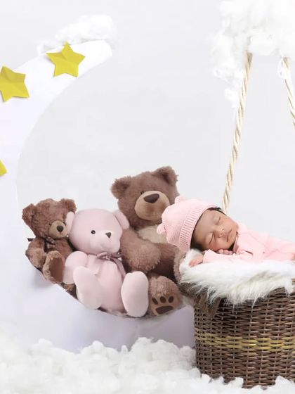 A dreamy moon and stars theme, with a newborn sleeping peacefully among fluffy clouds and soft teddy bears. A perfect setup for a celestial-inspired photoshoot.